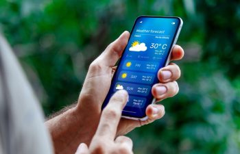 Man outdoors checking weather forecast on his mobile phone.