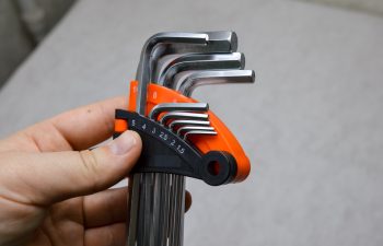 Hand holding a set of metal hex keys in orange and black holder. Tool kit, repair, maintenance, and DIY equipment concept.